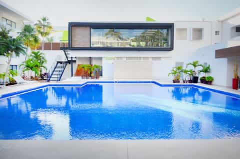 Resort swimming pool with blue water, modern white building, and palm trees