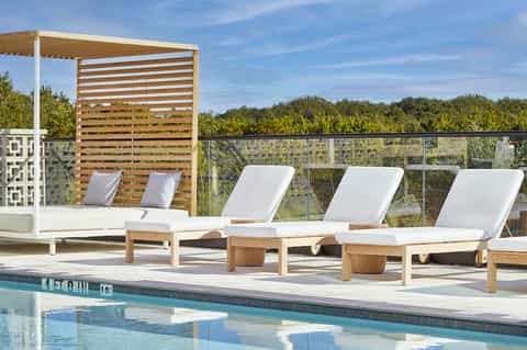 Poolside lounge chairs with umbrellas and wooden pergola shade structure