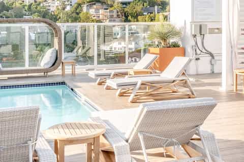 Rooftop pool deck with lounge chairs, circular window, and city skyline views