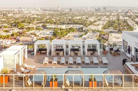 Rooftop pool deck with cabanas overlooking sprawling cityscape and palm trees