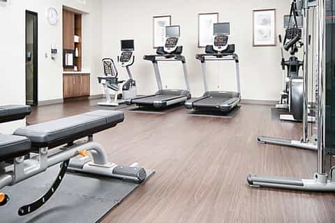 Fitness center with treadmills, exercise bikes, weights, and wooden flooring