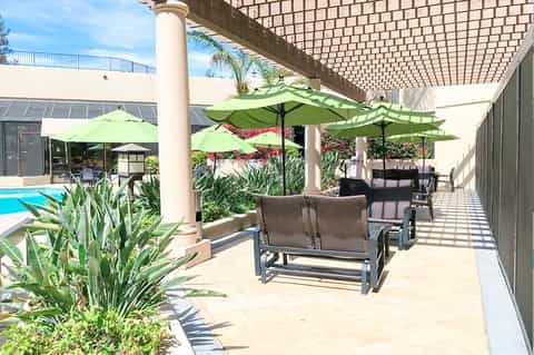 Shaded poolside seating area with green umbrellas and lounge chairs