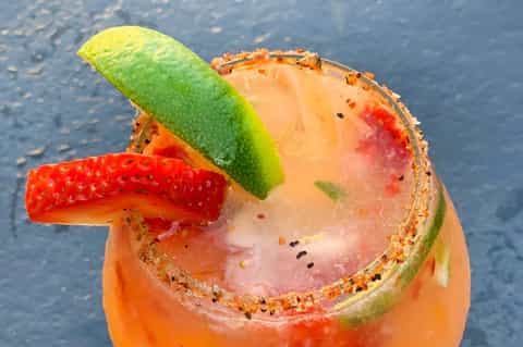 Colorful tropical cocktail with lime slice and spiced rim served poolside