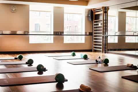 Modern fitness studio with yoga mats, green weights, and full-length mirrors overlooking city