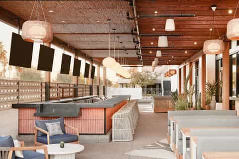 Modern rooftop bar and lounge with wooden ceiling, pendant lights, and seating areas