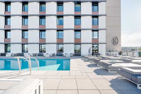 Resort rooftop pool area with lounge chairs and modern white building facade