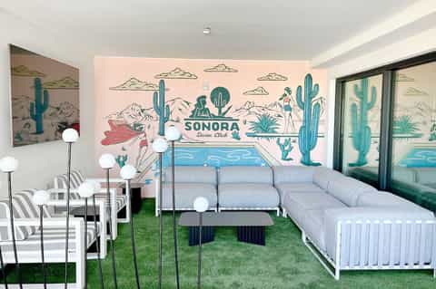 Modern lounge area with desert-themed mural, sofa, and artificial grass
