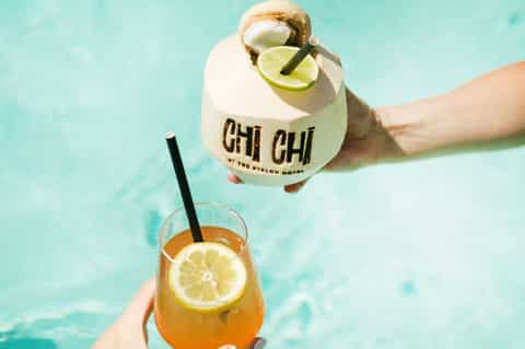 Hand holding tropical drink branded with 'CHI CHI' at the Avalon Hotel pool