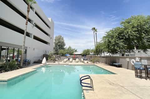 Resort swimming pool with lounge chairs and umbrellas beside modern building