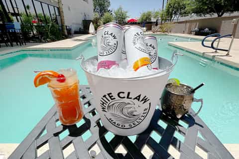 Poolside drink station with White Claw beverages and cocktails by turquoise pool
