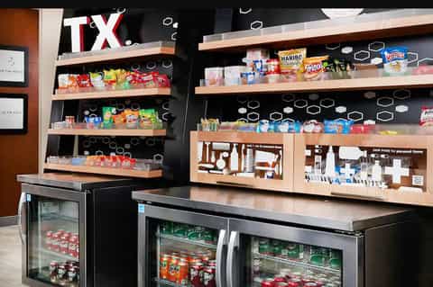 Snack bar display with shelves of candies, chips, and beverages with refrigerated cases