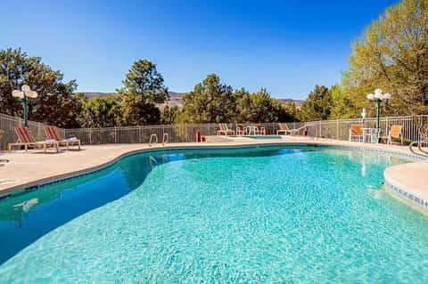 Resort swimming pool with clear blue water, lounge chairs, and scenic mountain views