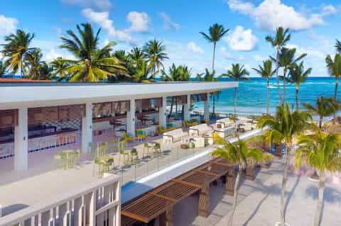 Modern beachfront bar and lounge with ocean view, palm trees, and comfortable seating areas