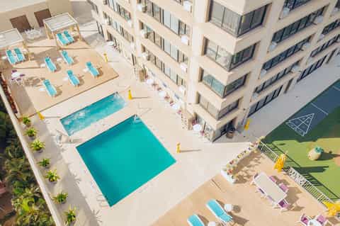 Aerial view of resort pools and deck with turquoise water and colorful lounge chairs