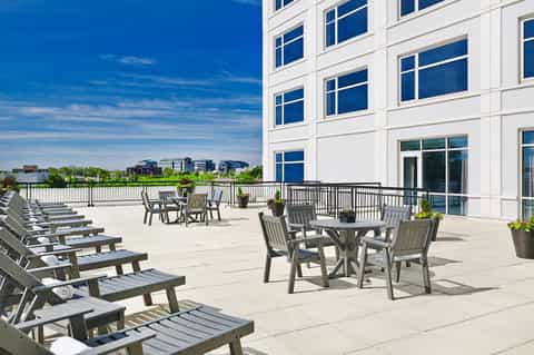 Waterfront terrace with lounge chairs, dining tables, and scenic river views under clear blue sky