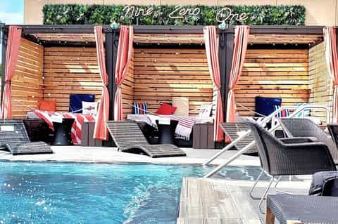 Resort pool cabanas with red and white striped curtains and wooden slat walls overlooking swimming pool
