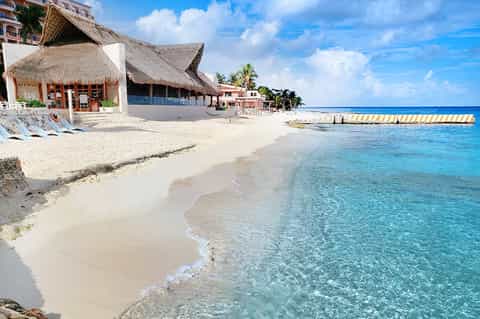 Tropical beach resort with thatched-roof bungalows, white sand, and crystal-clear turquoise water
