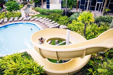 Aerial view of resort with white water slide, swimming pool, tropical landscaping and guest buildings