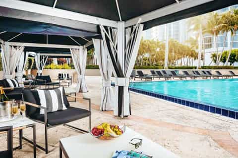 Modern cabana lounge with black and white striped seating overlooking turquoise pool