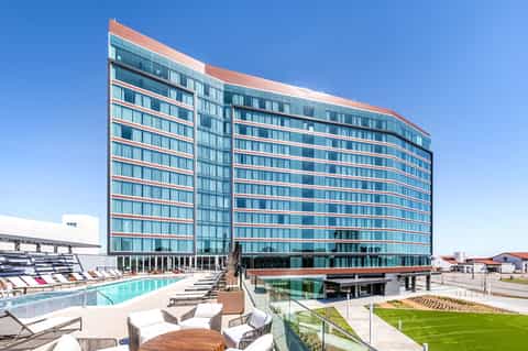 Contemporary hotel building with curved glass facade and pool lounge area