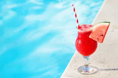 Red tropical cocktail with watermelon slice at poolside