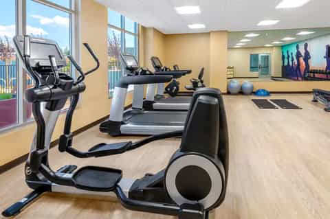 Modern fitness center with elliptical machines, treadmills, and exercise equipment by large windows