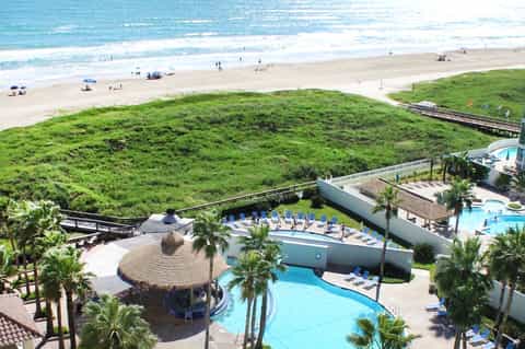 Beachfront resort pools and facilities overlooking sandy beach with ocean and dunes