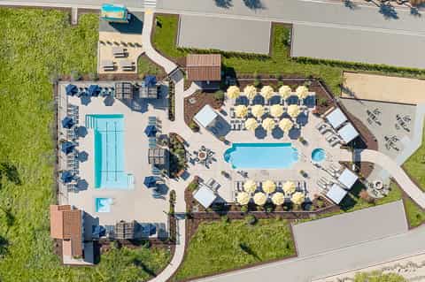 Overhead view of resort with two pools, yellow umbrellas, lounge chairs, and manicured grounds