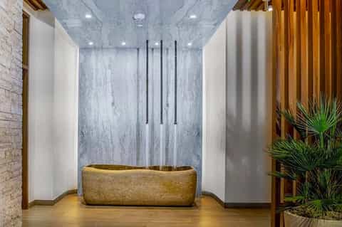 Modern spa bathroom with large stone soaking tub and marble waterfall shower