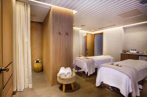Spa treatment room with two massage beds, wooden accents, and ambient lighting