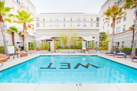 Elegant resort pool with LAM logo, palm trees, and classic hotel courtyard architecture