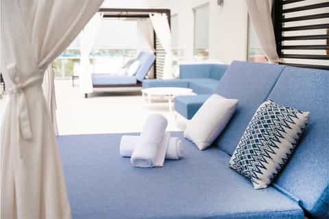 Modern lounge area with blue upholstered seating, white pillows, and ocean view through floor-to-ceiling windows
