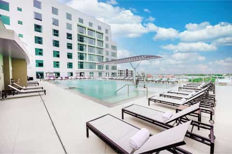Modern hotel rooftop pool with lounge chairs and architectural shade structure