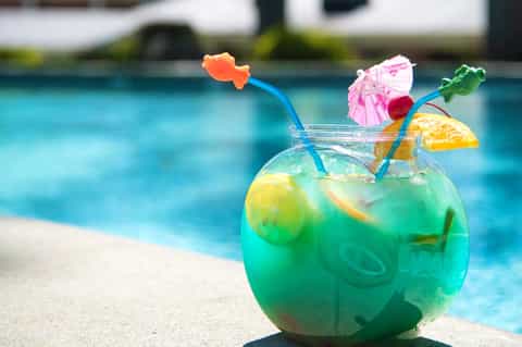 Colorful tropical cocktail with flower and fruit garnishes poolside