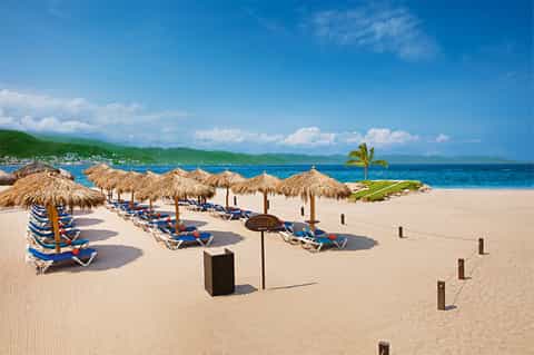 Beach club with thatched umbrellas, loungers, and ocean view