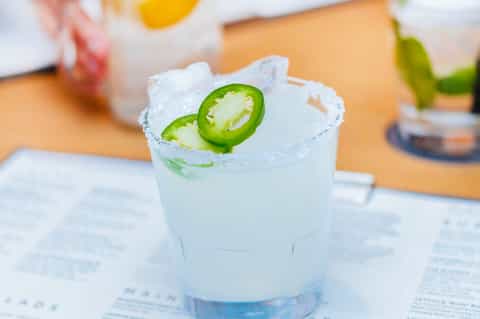 Spicy margarita with jalapeño slices and salt rim on a sunny patio