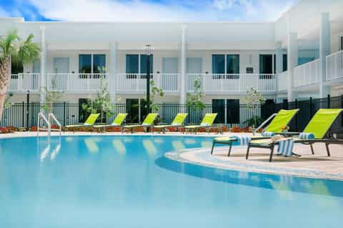 Modern resort pool with lime green lounge chairs and white building backdrop