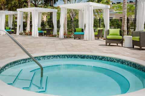 Circular hot tub surrounded by white cabanas and tropical landscaping near the resort pool