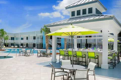 Resort pool area with bright green umbrellas, white pavilion, and hotel buildings