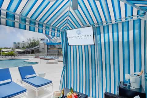 Waterstone Resort & Marina pool area with blue and white striped cabana tent and lounge chairs