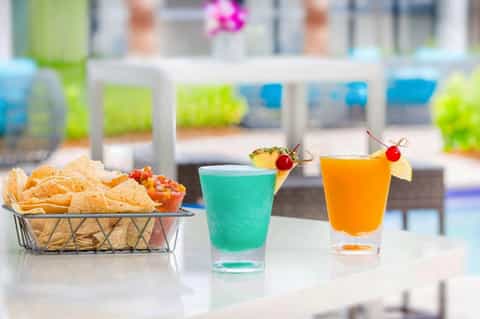 Poolside cocktails and appetizers with tropical drinks and chips on a white table