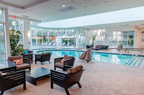 Indoor heated pool with lounge chairs and large windows overlooking grounds
