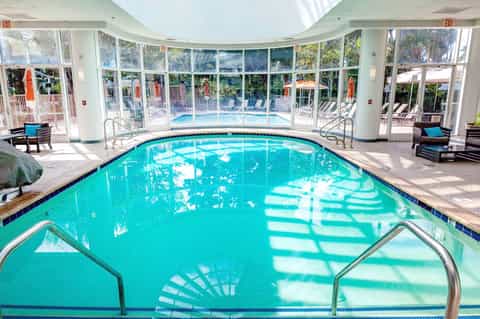 Indoor heated pool with large windows overlooking outdoor pool area