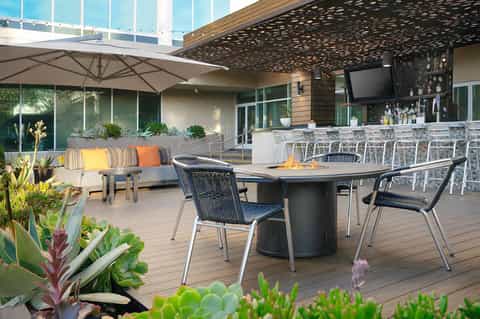 Outdoor rooftop terrace with lounge seating, dining tables, and landscape views