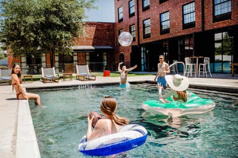 Family enjoying urban rooftop pool at brick resort with inflatable floats