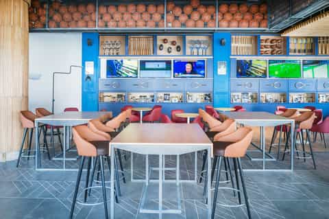 Sports bar lounge with blue storage wall, basketball displays, and high-top tables