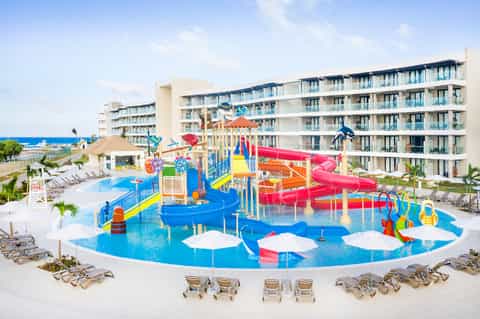 Vibrant water park with blue splash pad, colorful slides, and multi-story resort building