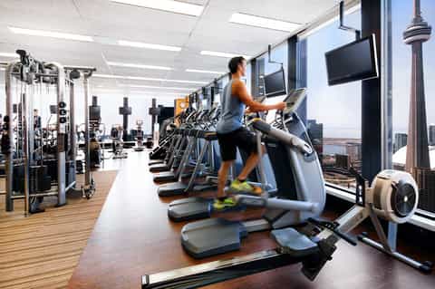 Fitness center with cardio equipment, large windows overlooking city skyline and CN Tower