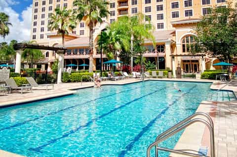 Resort lap pool with lane dividers, lounge chairs, and tropical resort building backdrop