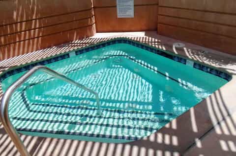Indoor hot tub with turquoise water, wooden walls, natural light, and tile accents